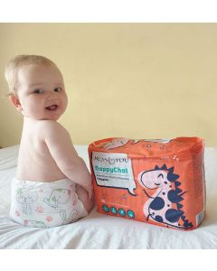 A cozy baby sits on a bed in Mum & You Eco Nappies—super soft, breathable, and dry for 12 hours, with fun Nappychat characters for bonding!