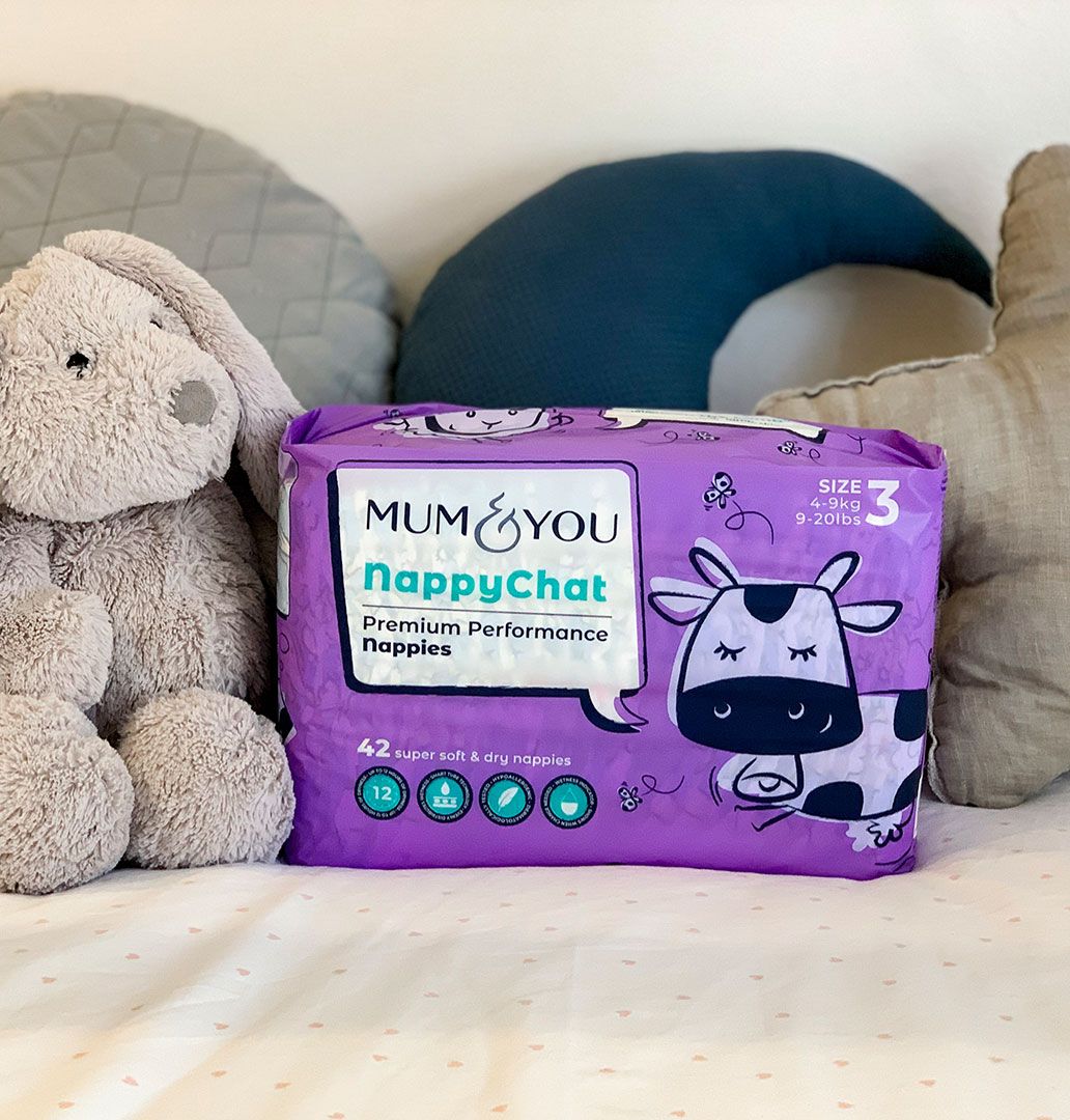 A cuddly stuffed animal and a Mum & You nappy bag rest on the bed, creating a cozy atmosphere with eco-friendly nappies for every adventure!